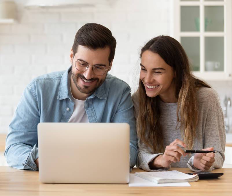 Couple comparing electricity plans online at home while reviewing household energy costs
